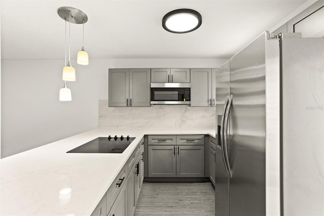 kitchen featuring gray cabinetry, light stone countertops, hanging light fixtures, stainless steel appliances, and decorative backsplash