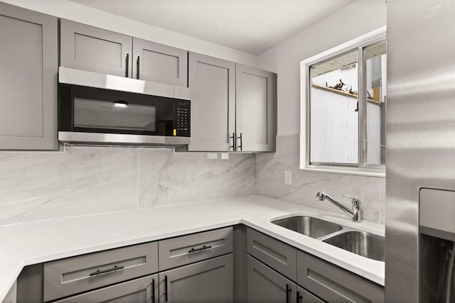 kitchen with gray cabinetry, sink, and tasteful backsplash