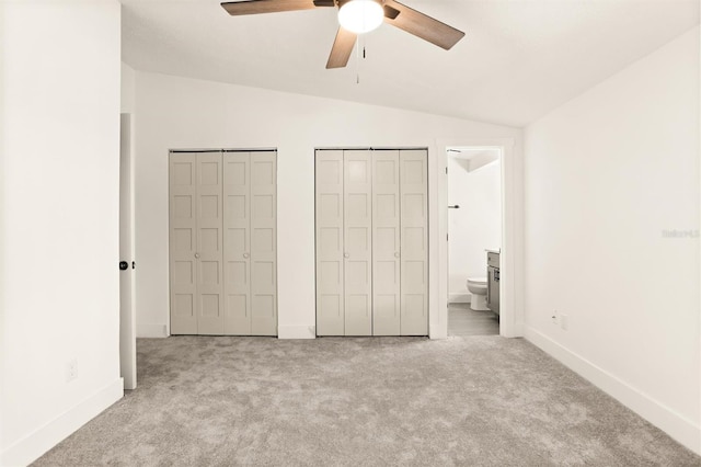 unfurnished bedroom featuring ensuite bathroom, ceiling fan, light colored carpet, and vaulted ceiling