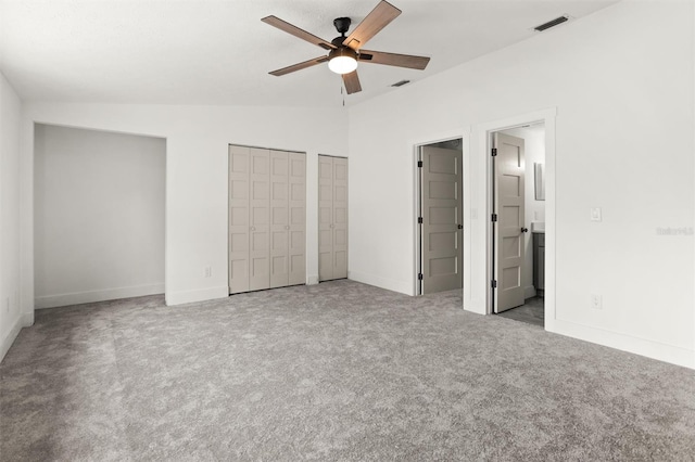 unfurnished bedroom featuring light carpet, ensuite bath, two closets, vaulted ceiling, and ceiling fan