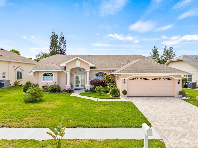 ranch-style house featuring a front yard, a garage, and central AC unit