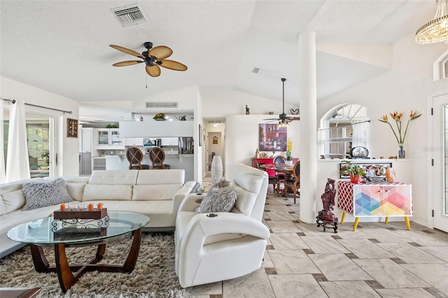 living room with a textured ceiling, ceiling fan, and vaulted ceiling