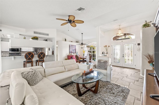 tiled living room featuring lofted ceiling, a textured ceiling, ceiling fan, and french doors