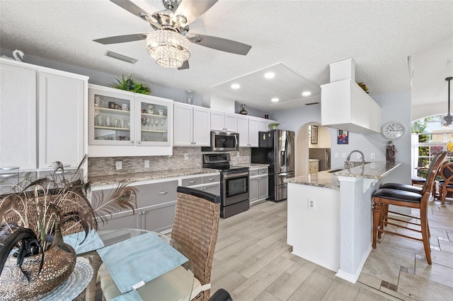 kitchen featuring stainless steel appliances, sink, white cabinetry, kitchen peninsula, and backsplash