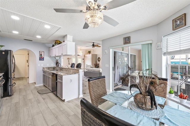 kitchen featuring sink, white cabinets, light stone countertops, dishwashing machine, and stainless steel fridge