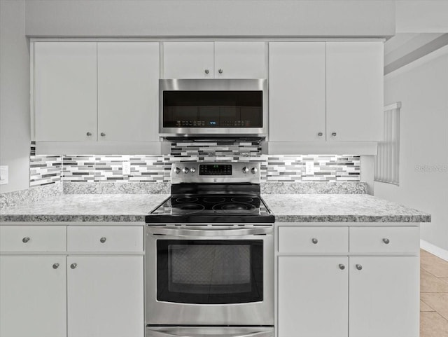 kitchen with stainless steel appliances, white cabinetry, tasteful backsplash, and light tile patterned floors