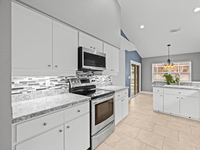 kitchen featuring sink, appliances with stainless steel finishes, tasteful backsplash, white cabinets, and decorative light fixtures