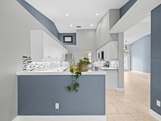 kitchen featuring decorative light fixtures, white cabinets, decorative backsplash, kitchen peninsula, and stainless steel appliances