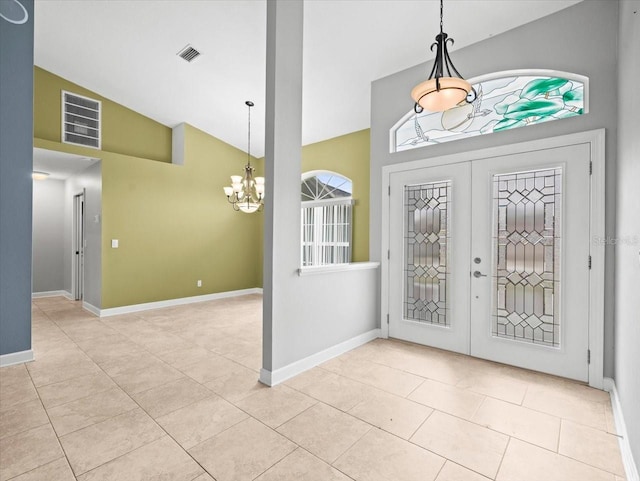 foyer entrance with light tile patterned flooring, high vaulted ceiling, an inviting chandelier, and french doors