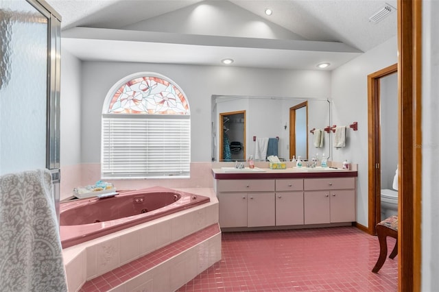 bathroom with lofted ceiling, tile patterned flooring, tiled bath, toilet, and vanity