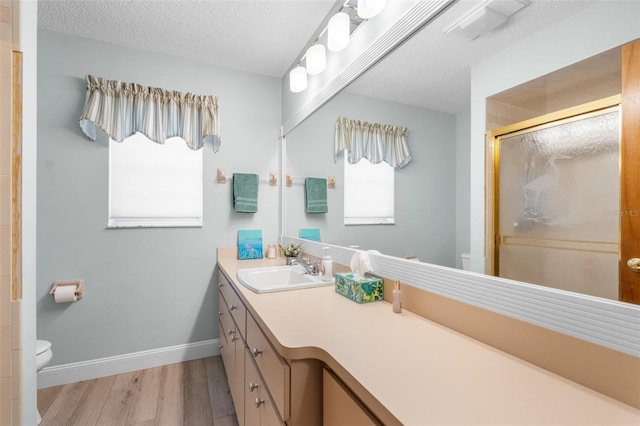 bathroom featuring toilet, hardwood / wood-style flooring, a textured ceiling, an enclosed shower, and vanity