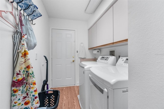 laundry room with washer and dryer, cabinets, and wood-type flooring