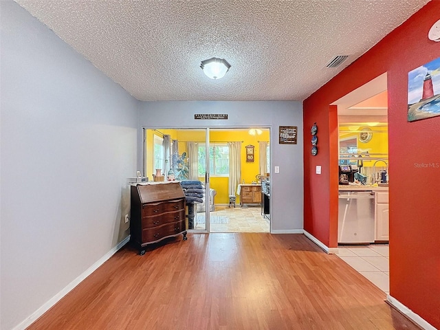 corridor featuring a textured ceiling and light wood-type flooring