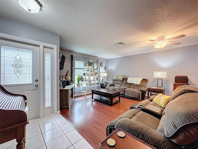 living room featuring a textured ceiling, light hardwood / wood-style flooring, and ceiling fan