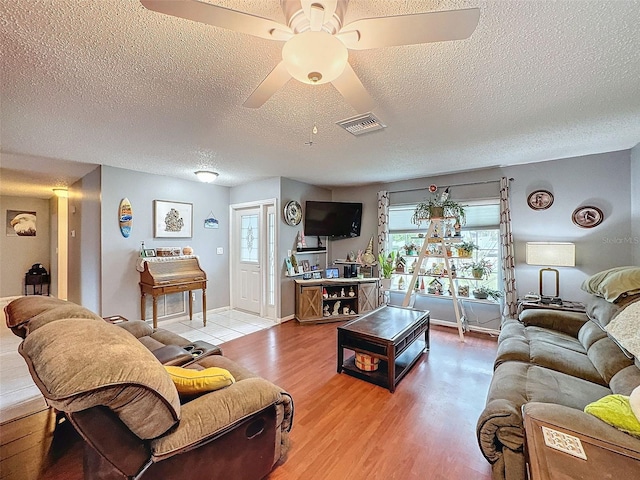 living room featuring hardwood / wood-style flooring, ceiling fan, and a textured ceiling