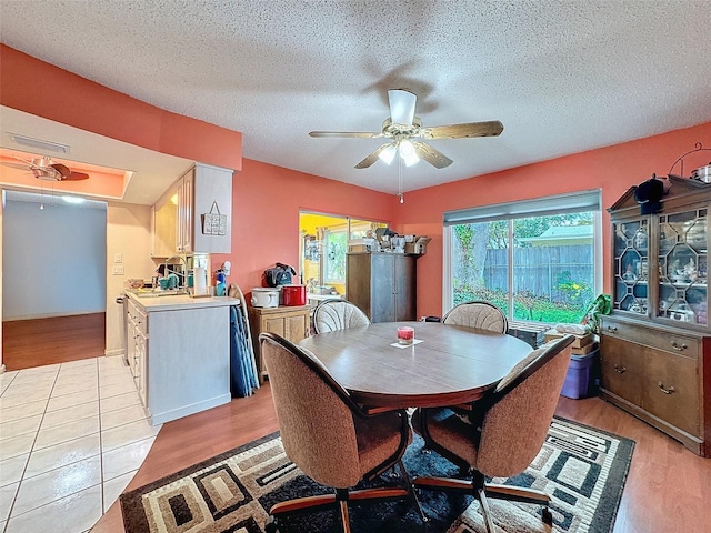 dining room with light wood-type flooring, a textured ceiling, and ceiling fan