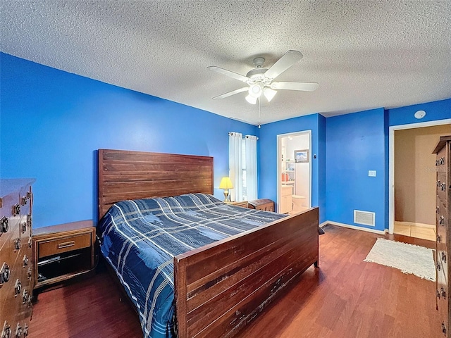 bedroom with a textured ceiling, ceiling fan, and dark hardwood / wood-style floors