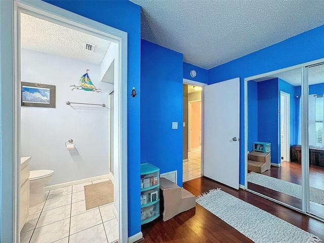 bathroom with tile patterned floors, a textured ceiling, and toilet