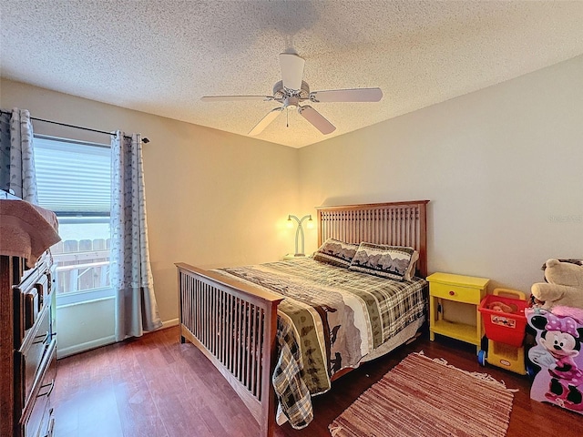 bedroom featuring ceiling fan, dark hardwood / wood-style floors, and a textured ceiling