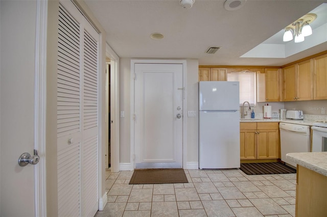 kitchen featuring sink, white appliances, and light brown cabinetry