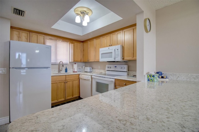 kitchen with light brown cabinetry, sink, light stone countertops, a tray ceiling, and white appliances