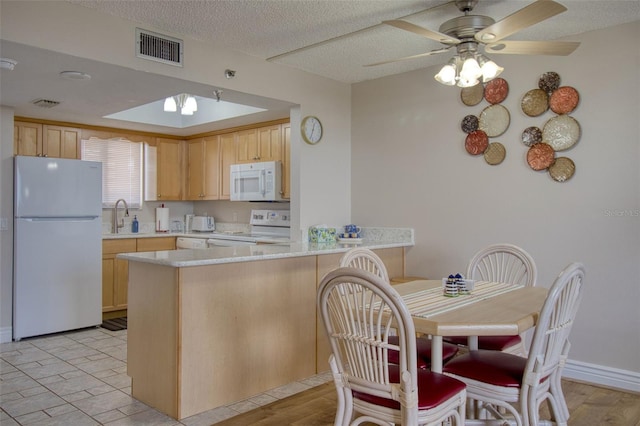 kitchen with kitchen peninsula, light brown cabinetry, ceiling fan, sink, and white appliances