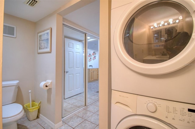 laundry room featuring stacked washer and clothes dryer and light tile patterned flooring