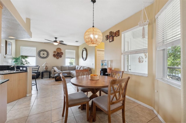 tiled dining room with ceiling fan with notable chandelier, sink, and a wealth of natural light