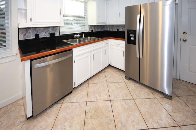 kitchen featuring appliances with stainless steel finishes, tasteful backsplash, sink, white cabinetry, and light tile patterned flooring