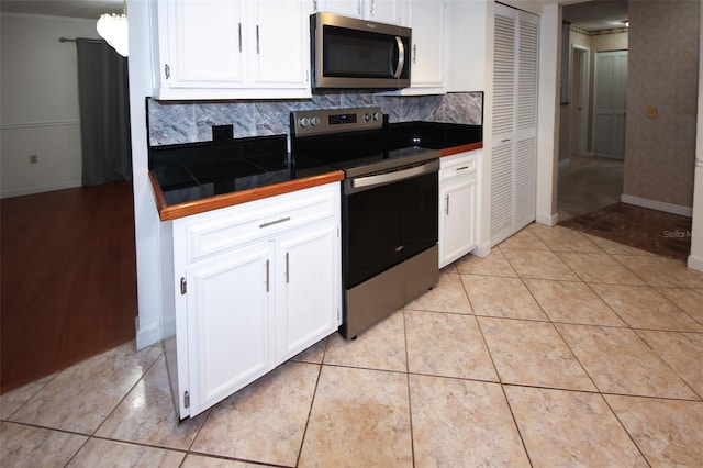 kitchen featuring tasteful backsplash, white cabinets, stainless steel appliances, and light tile patterned floors