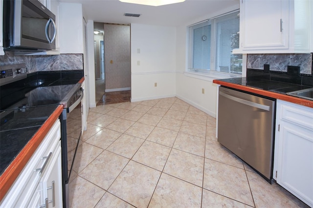 kitchen featuring appliances with stainless steel finishes, backsplash, white cabinetry, and tile counters