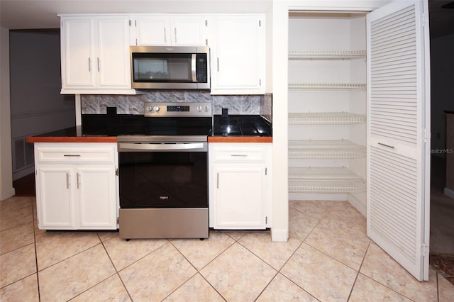 kitchen featuring appliances with stainless steel finishes, light tile patterned floors, and white cabinetry