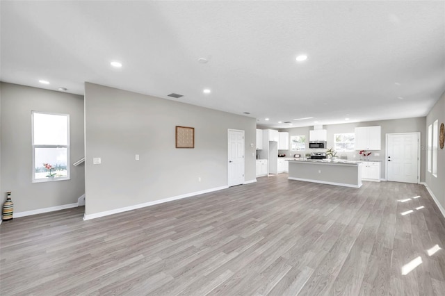 unfurnished living room featuring a textured ceiling and light wood-type flooring