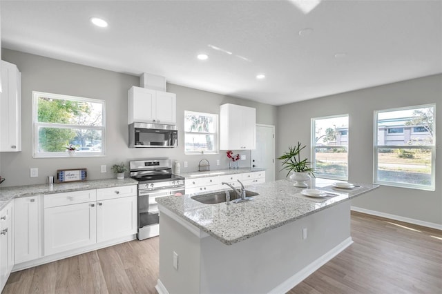 kitchen featuring light stone countertops, sink, stainless steel appliances, a kitchen island with sink, and white cabinets