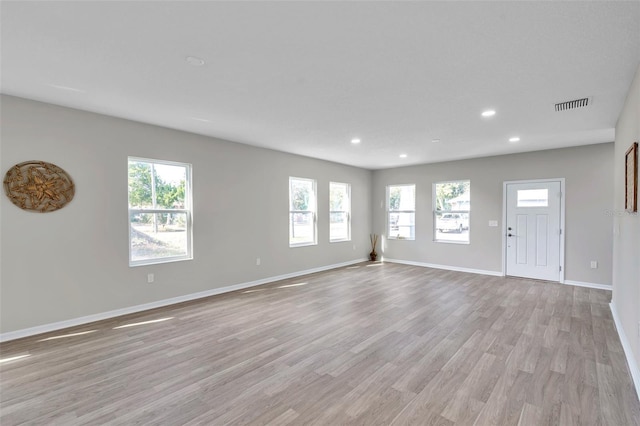 unfurnished living room featuring a wealth of natural light and light hardwood / wood-style flooring