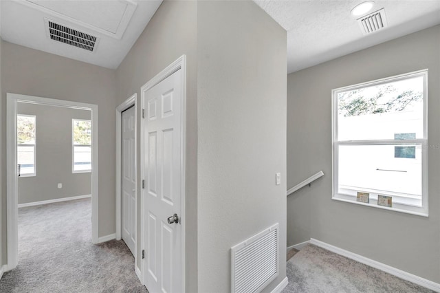 hallway featuring a textured ceiling and light carpet