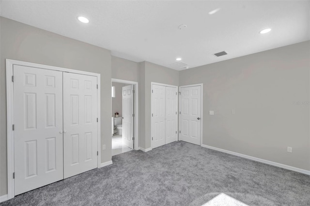 unfurnished bedroom featuring carpet flooring and two closets