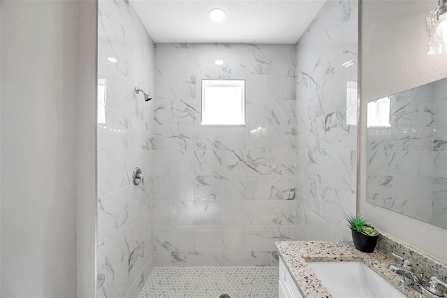 bathroom with a tile shower and vanity