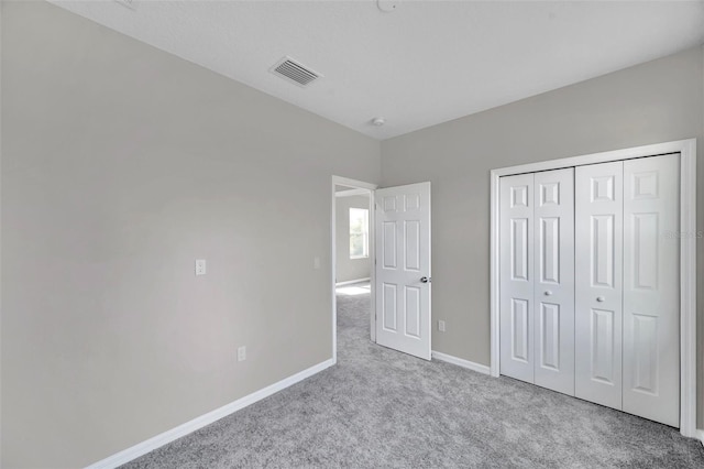 unfurnished bedroom featuring light carpet and a closet