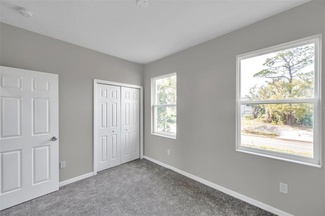 unfurnished bedroom with light colored carpet and a closet