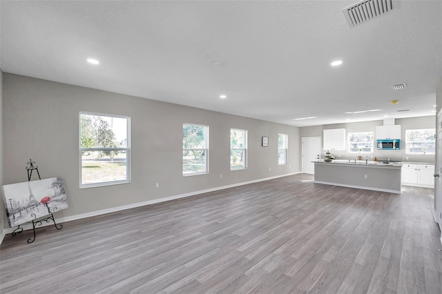 unfurnished living room featuring plenty of natural light and light wood-type flooring