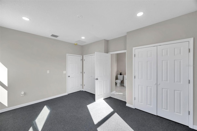 unfurnished bedroom with dark colored carpet and ensuite bath