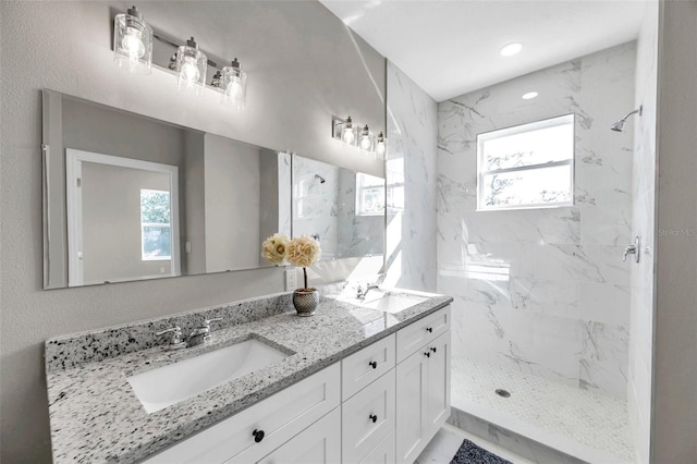 bathroom with a tile shower and vanity