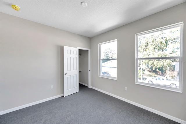 unfurnished bedroom featuring a textured ceiling and dark colored carpet