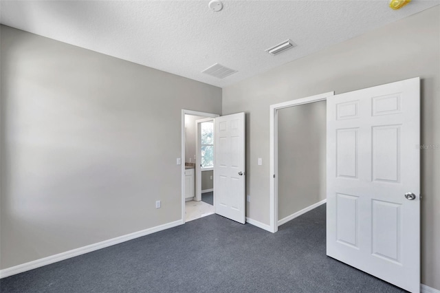 unfurnished bedroom featuring dark colored carpet and a textured ceiling