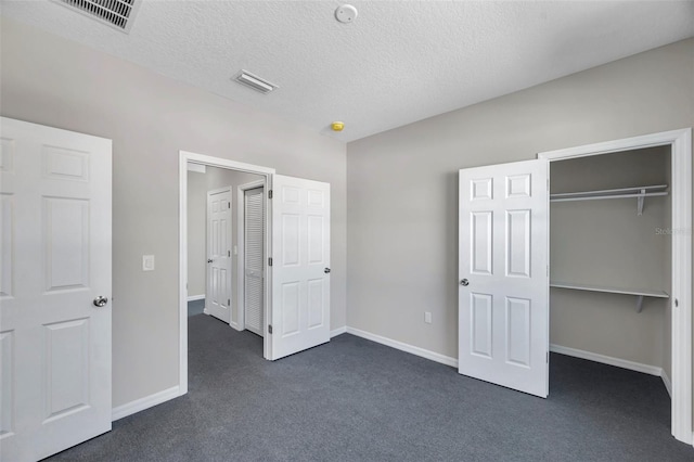 unfurnished bedroom with dark carpet, a textured ceiling, and a closet