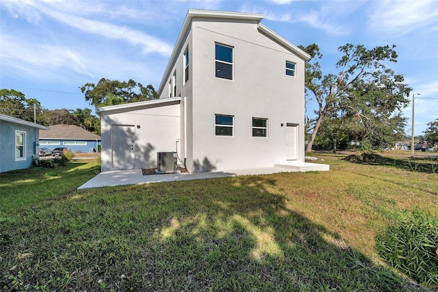 rear view of house featuring a patio, a yard, and central AC