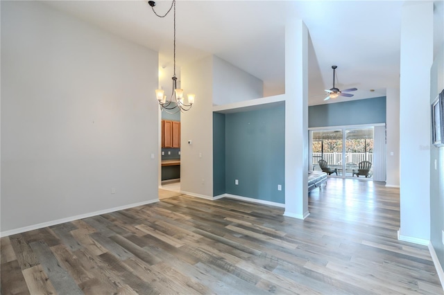 unfurnished room featuring ceiling fan with notable chandelier, hardwood / wood-style floors, and high vaulted ceiling