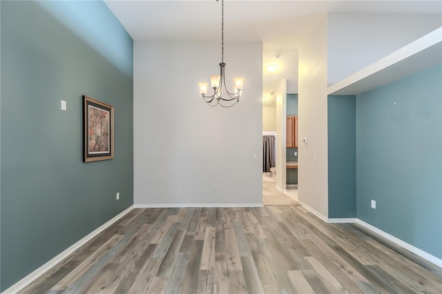 empty room with an inviting chandelier, a towering ceiling, and hardwood / wood-style floors