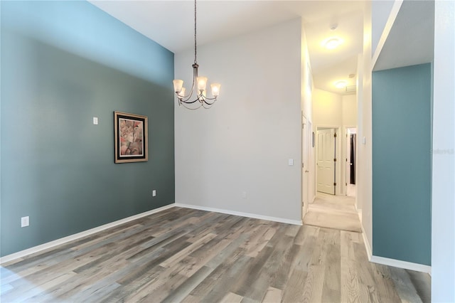 unfurnished room with a high ceiling, wood-type flooring, and an inviting chandelier